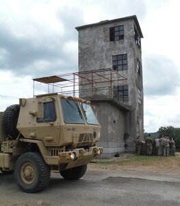 Members of the 841st Engineer Battalion, U.S. Army Reserve, conduct a construction update brief while an M1157 10 Ton Dump Truck heads to a site improvement location at Novo Selo Training Area, Bulgaria as part of Operation Resolute Castle 16, July 20, 2016. (U.S. Army photo by Capt. Jose F. Lopez Jr., 841st Eng. Bn., United States Army Reserve)