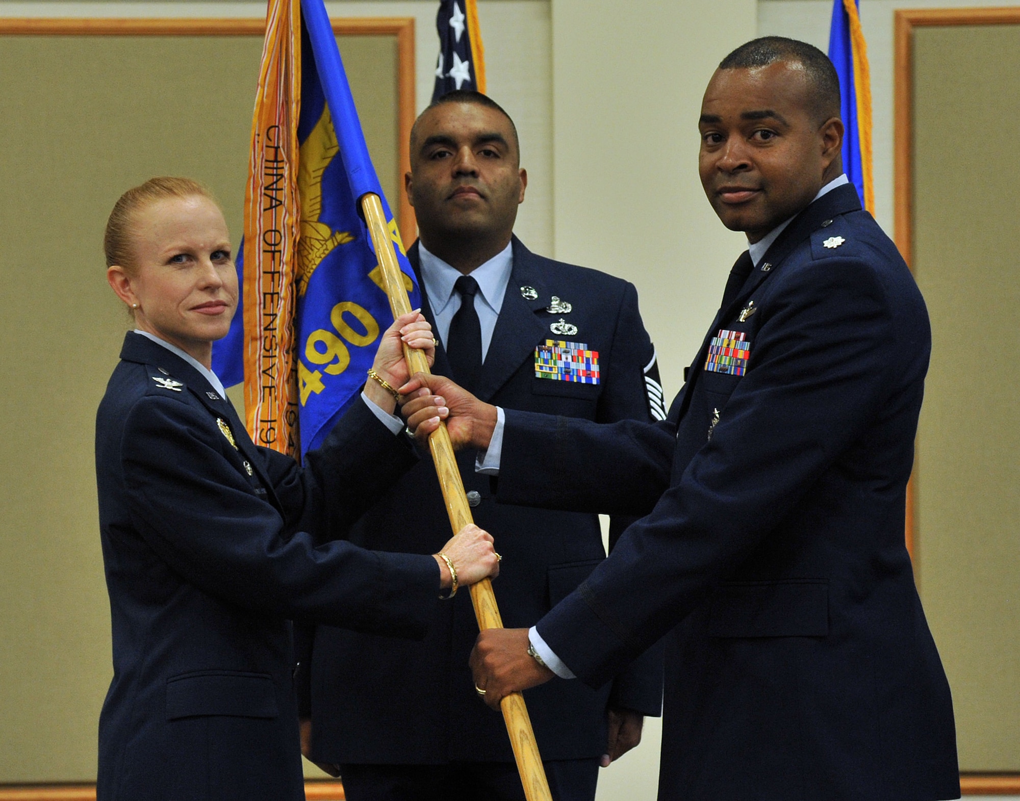 Lt. Col. Tytonia Moore, right, accepts command of the 490th Missile Squadron from Col. Anita Feugate Opperman, 341st Operations Group commander, during a change of command ceremony at the Grizzly Bend July 22, 2016. Master Sgt. Gabriel Portillo-Ramos, 490 MS superintendent, looks on. (U.S. Air Force photo/John Turner)