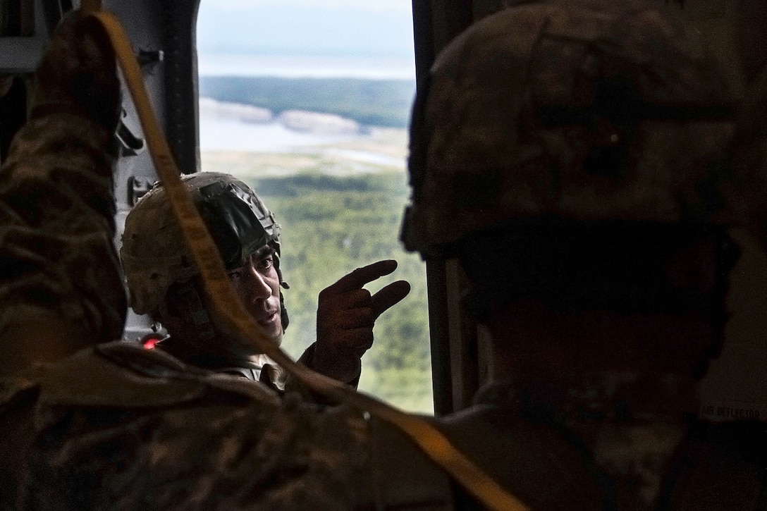 An Army jumpmaster communicates using hand signals before a training jump out of a C-17 Globemaster III to prepare the  for Arctic Thunder Open House at Joint Base Elmendorf-Richardson, Alaska, July 20, 2016. Air Force photo by Senior Airman James Richardson  