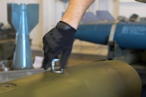 An Airman from the 5th Munitions Squadron, tighten a lug onto an inert bomb at Minot Air Force Base, N.D., July 20, 2016. These lugs are used to hook a bomb onto an aircraft. (U.S. Air Force photo/Airman 1st Class Jessica Weissman)