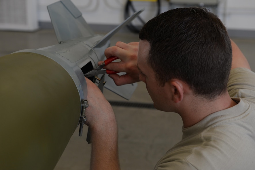 Airman 1st Class Derek Merkley, a conventional munitions crew member assigned to the 5th Munitions Squadron, installs a fuse drive unit to an inert bomb at Minot Air Force Base, N.D., July 20, 2016. After installing the fin, the individual nomenclature is spray painted to identify the bomb. (U.S. Air Force photo/Airman 1st Class Jessica Weissman)