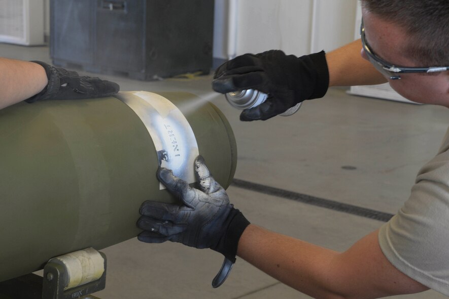 An Airman from the 5th Munitions Squadron, spray paints the nomenclature “inert” onto a bomb at Minot Air Force Base, N.D., July 20, 2016. An inert bomb is a fake bomb used for training purposes. (U.S. Air Force photo/Airman 1st Class Jessica Weissman)