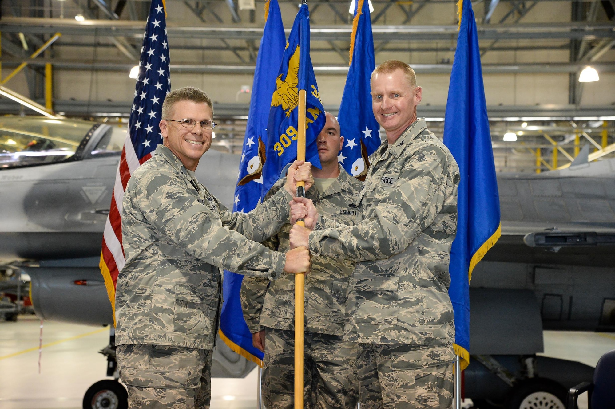 Brig. Gen. Steven J. Bleymaier, Ogden Air Logistics Complex commander (left), passes the 309th Aircraft Maintenance Group guidon to incoming Group Commander, Col. Jon A. Eberlan, during a change of command ceremony at Hill AFB, Utah, July 8, 2016. (U.S. Air Force photo by R. Nial Bradshaw)