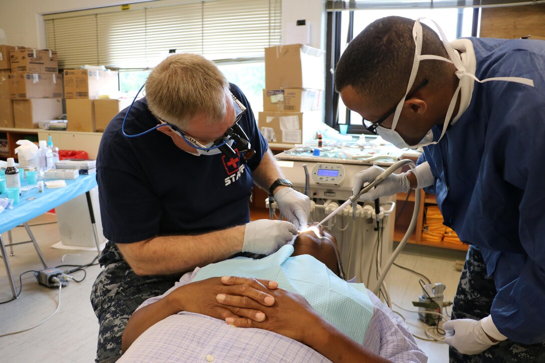 Cmdr. Ryan Schmidt, a dentist with Expeditionary Medical Facility Bethesda out of Bethesda, Md., assisted by HM3 Velzson Davidson, a dental technician, performs a dental procedure at the Healthy Cortland Innovative Readiness Training event, July 18, 2016. Healthy Cortland is one of the IRT events that provide real-world training in a joint civil-military environment while delivering world-class medical care to the people of Cortland, N.Y., from July 15-24.