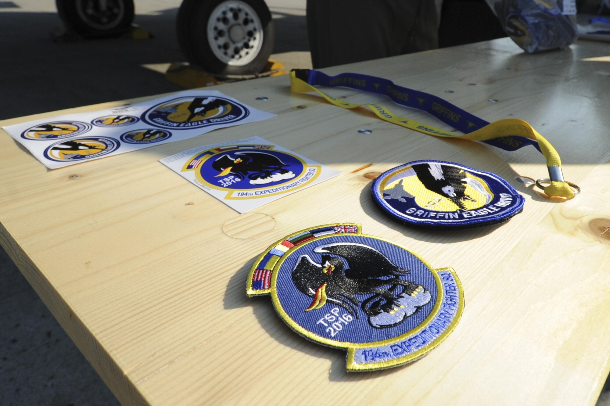 A collection of patches, stickers and lanyards emblazoned with the 194th Expeditionary Fighter Squadron logo rest on a table during the Romanian air force's 71st Air Base's air show and open house at Campia Turzii, Romania, July 23, 2016. The aviation demonstration took place during the middle of the 194th EFS' six-month long theater security package deployment to Europe in support of Operation Atlantic Resolve, which aims to bolster the U.S.'s continued commitment to the collective security of NATO and dedication to the enduring peace and stability in the region. The unit, comprised of more than 200 CANG Airmen from the 144th Fighter Wing at Fresno ANG Base, Calif., as well as U.S. Air Force Airmen from the 52nd Fighter Wing at Spangdahlem Air Base, Germany, piloted, maintained and supported the deployment of 12 F-15Cs Eagle fighter aircraft throughout nations like Romania, Iceland, the United Kingdom, the Netherlands, Estonia and among others. The F-15Cs took to the skies alongside the 71st AB's MiG-21 fighter aircraft and Puma helicopters for both the airshow, the second engagement of its kind at Campia Turzii under Operation Atlantic Resolve, and the bilateral flight training, also known as Dacian Eagle 2016. (U.S. Air Force photo by Staff Sgt. Joe W. McFadden/Released)