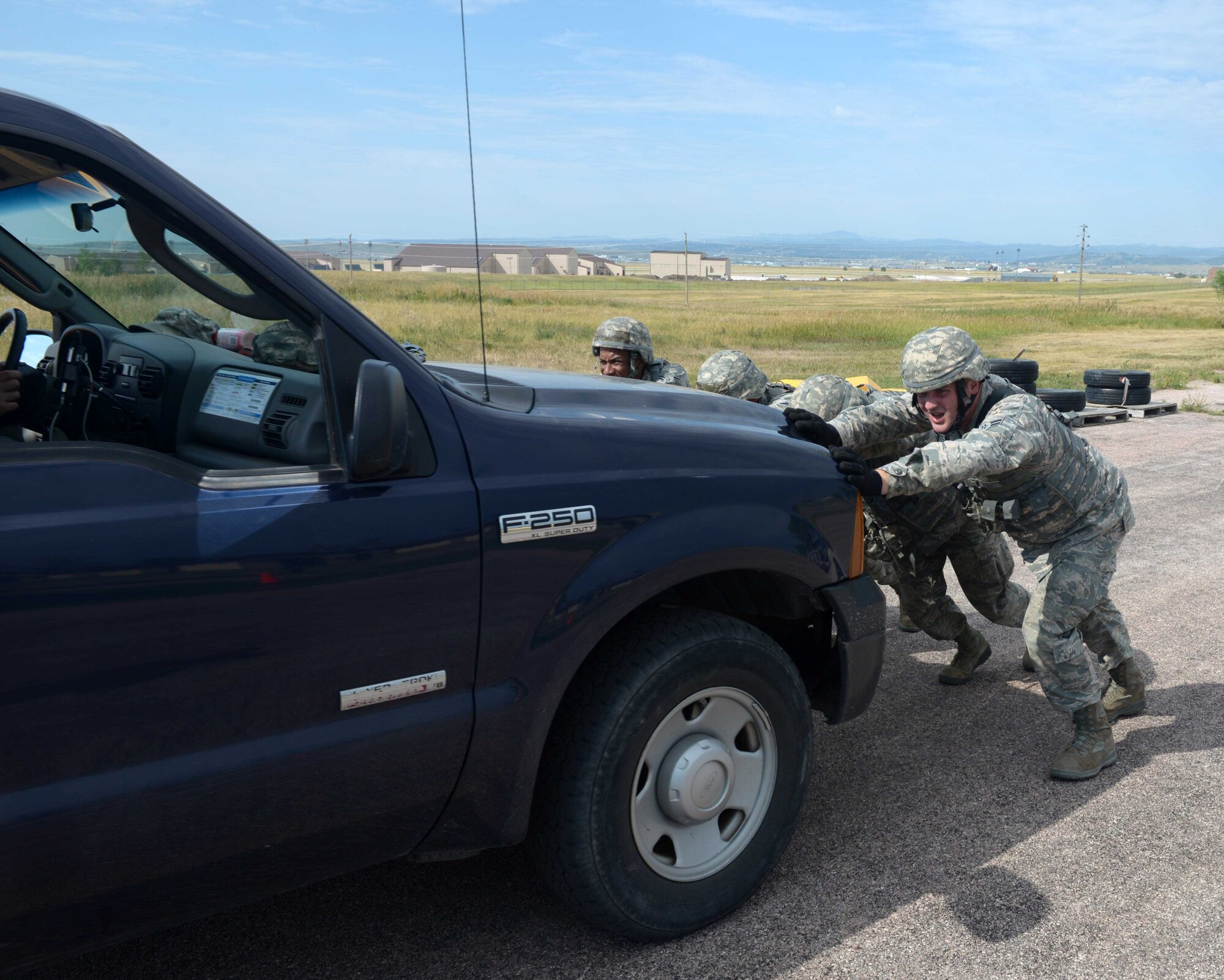 Airmen with the 28th Civil Engineer Squadron push a six-passenger vehicle during the Prime Base Engineer Emergency Force (BEEF) challenge at Ellsworth Air Force Base, S.D., July 22, 2016. The Six-PAX Push is an endurance event where four Airmen push a six-passenger vehicle for 100 yards. (U.S. Air Force photo by Airman Donald Knechtel)