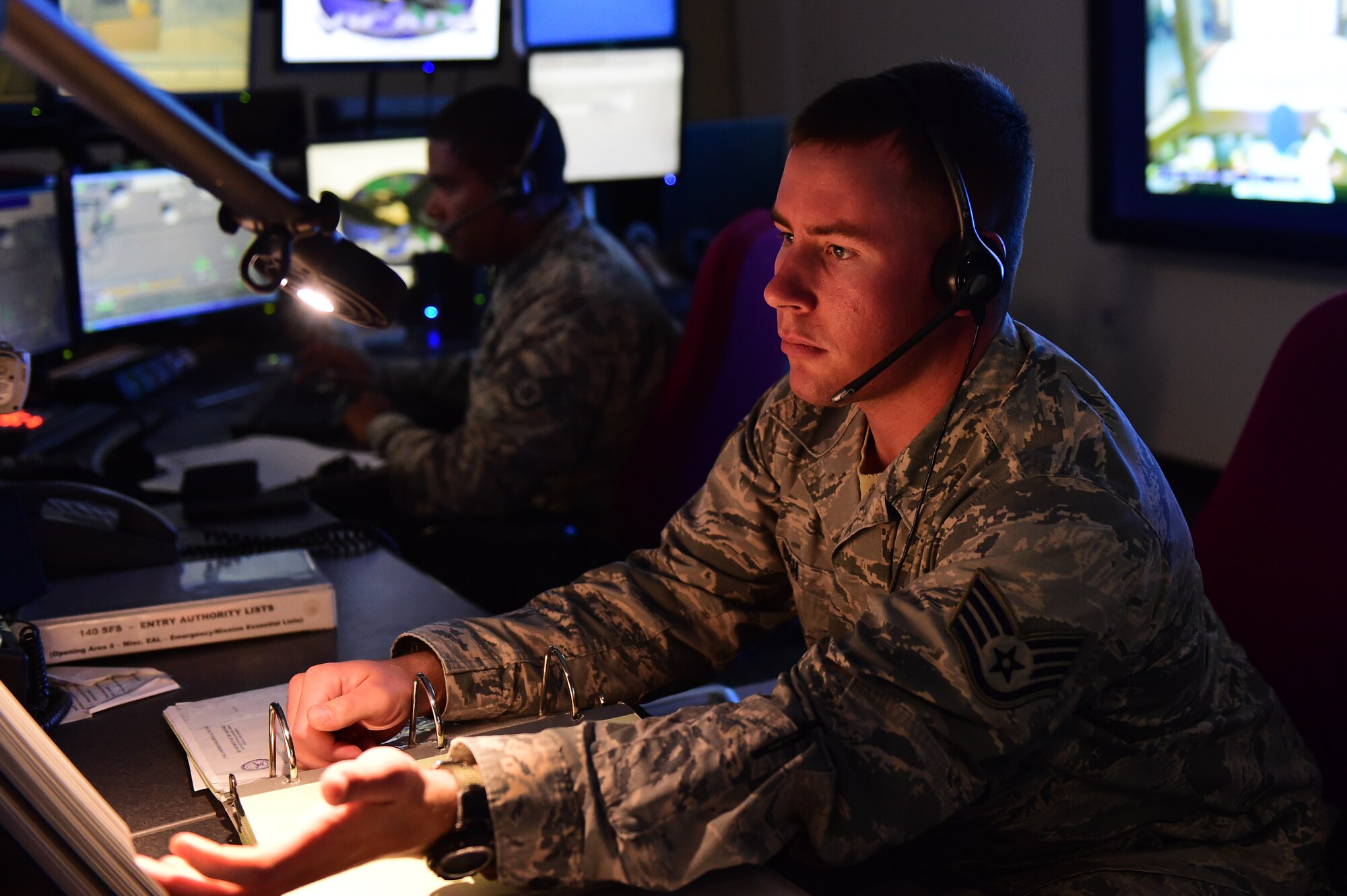 Staff Sgt. Tyler Bush, Base Defense Operations Center controller, and Staff Sgt. Alexander Parrilla, BDOC controller, review procedures July 20, 2016, at Buckley Air Force Base, Colo. BDOC maintains positive security of the base, controls the dispatch and alarm systems and entry control procedures while also providing emergency services to Buckley and local authorities. (U.S. Air Force photo by Airman 1st Class Gabrielle Spradling/Released)