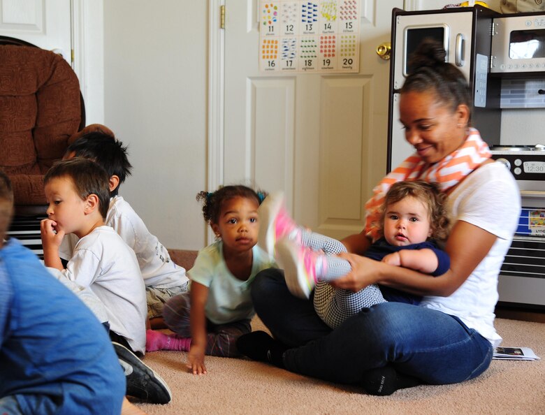 Ellen Prescott, Family Child Care provider, plays with Claire during a graduation ceremony June 24, 2016, at Malmstrom Air Force Base, Mont. Prescott is Claire’s primary care provider and has cared for Claire since she was 6 months old. (U.S. Air Force photo/2nd Lt. Annabel Monroe)