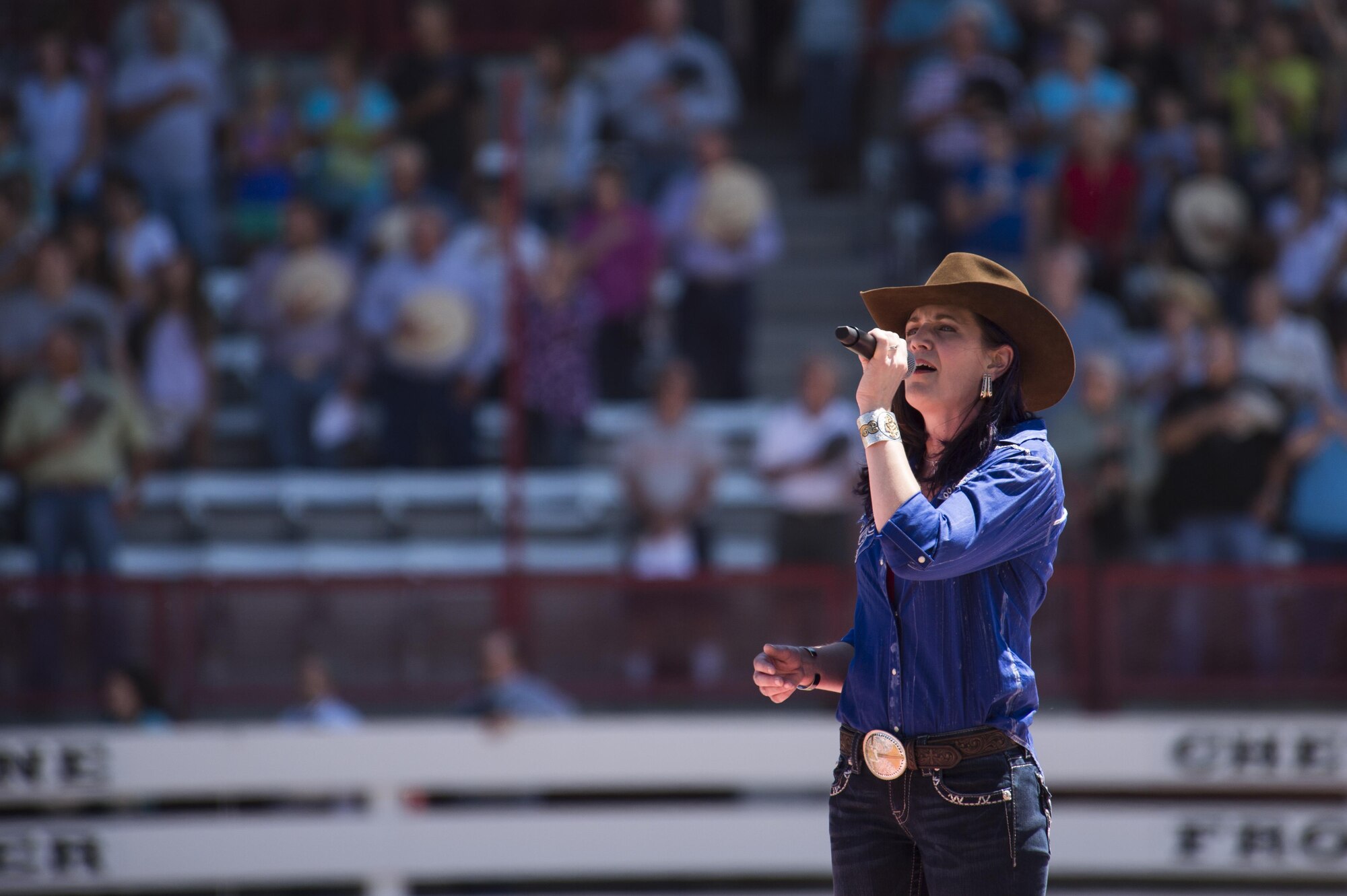 Kori Lance, spouse of Lt. Col. Robert Lance, 90th Civil Engineer Squadron commander, sings the National Anthem during Military Monday at Frontier Park in Cheyenne, Wyo., July 25, 2016. During this time, a massive flag carried by more than 100 volunteers was carried out and unfolded. (U.S. Air Force photo by Staff Sgt. Christopher Ruano)
