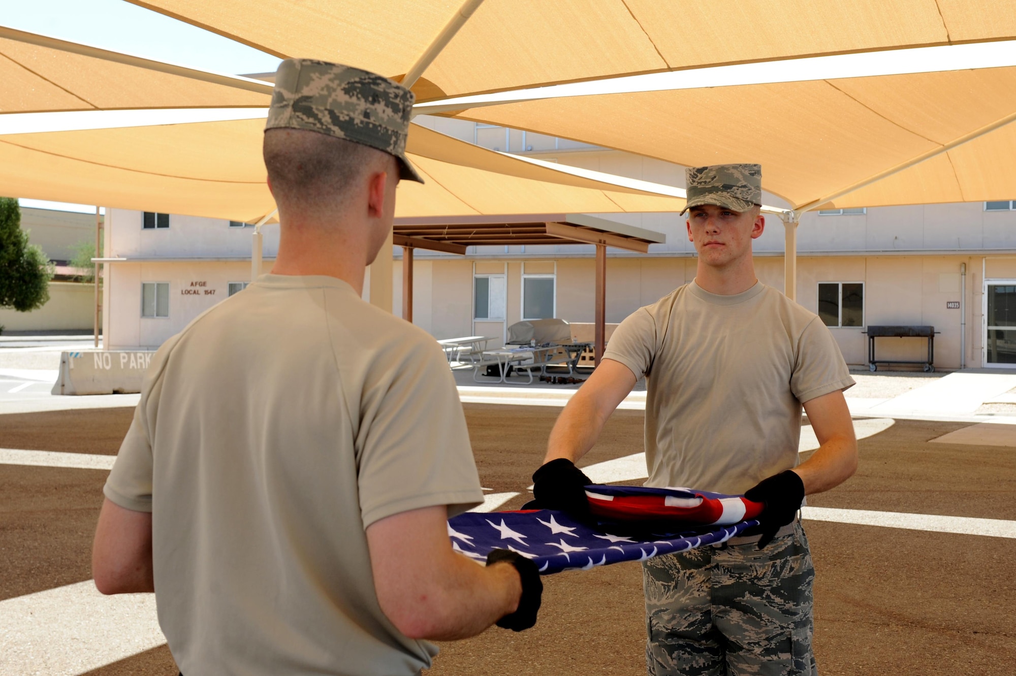 Senior Airman Kyle Morrison, 56 Operation Support Squadron, and Airman 1st Class Matthew Green, 56th Equipment Maintenance Squadron aerospace ground equipment apprentice, practice a ceremonial flag fold July 7, 2016 at Luke Air Force Base, Ariz. Flag folds are performed to honor those who have fallen and those who have retired from the military.
