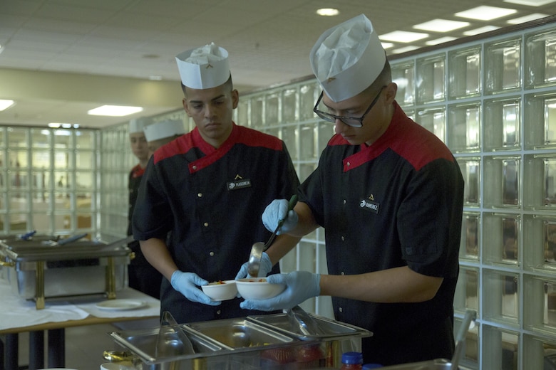 Lance Cpl. Diego Ramirez, left, and Pfc. Moises Plascencia prepare to serve a side dish to a panel of judges during the Futenma Mess Hall Chef of the Month competition July 22 on Marine Corps Air Station Futenma, Okinawa, Japan. The monthly competition is an opportunity for the Marines who are performing well in the workplace and seeking opportunities to better themselves through merit boards and other events. During the competition, the contestants must plan a full multi-course meal, cook the dishes and serve it to a panel of judges who evaluate their meal based on taste, appearance, originality and the Marines’ oral presentations explaining each course. Ramirez and Plascencia are food service specialists assigned to the MCAS Futenma Mess Hall. Ramirez is a Baker’s Hill, California, native. Plascencia is a Modesto, California, native.