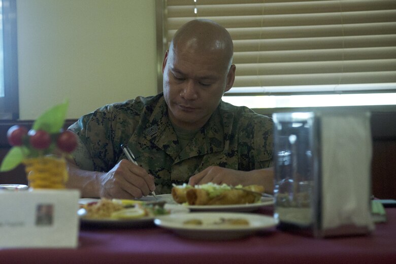 Sgt. Maj. Misitupa Tueichi writes comments while serving on the judges panel for the Futenma Mess Hall Chef of the Month competition July 22 on Marine Corps Air Station Futenma, Okinawa, Japan. The monthly competition is an opportunity for the Marines who are performing well in the workplace and seeking opportunities to better themselves through merit boards and other events. During the competition, the contestants must plan a full multi-course meal, cook the dishes and serve it to a panel of judges who evaluate their meal based on taste, appearance, originality and the Marines’ oral presentations explaining each course. Tueichi is the sergeant major of Marine Aircraft Control Group 18, 1st Marine Aircraft Wing, III Marine Expeditionary Force and an American Samoa, native.