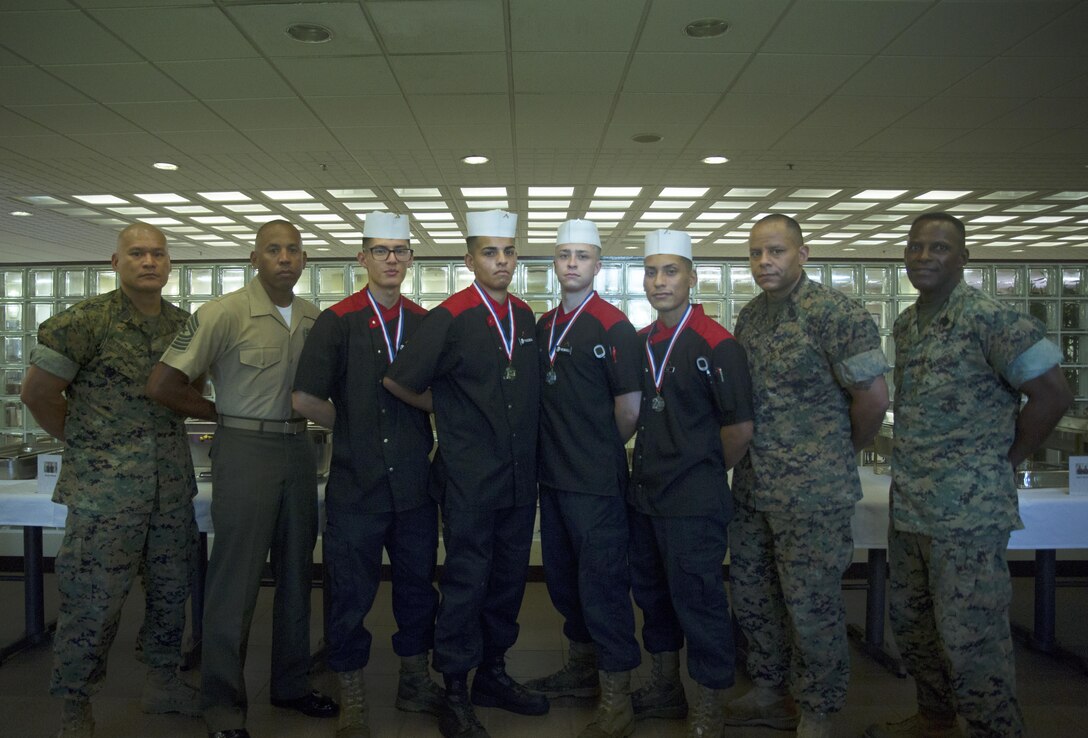 Competitors in the Futenma Mess Hall Chef of the Month competition pose for photos with the senior enlisted judges after receiving awards for their performance July 22 on Marine Corps Air Station Futenma, Okinawa, Japan. The monthly competition is an opportunity for the Marines who are performing well in the workplace and seeking opportunities to better themselves through merit boards and other events. During the competition, the contestants must plan a full multi-course meal, cook the dishes and serve it to a panel of judges who evaluate their meal based on taste, appearance, originality and the Marines’ oral presentations explaining each course.