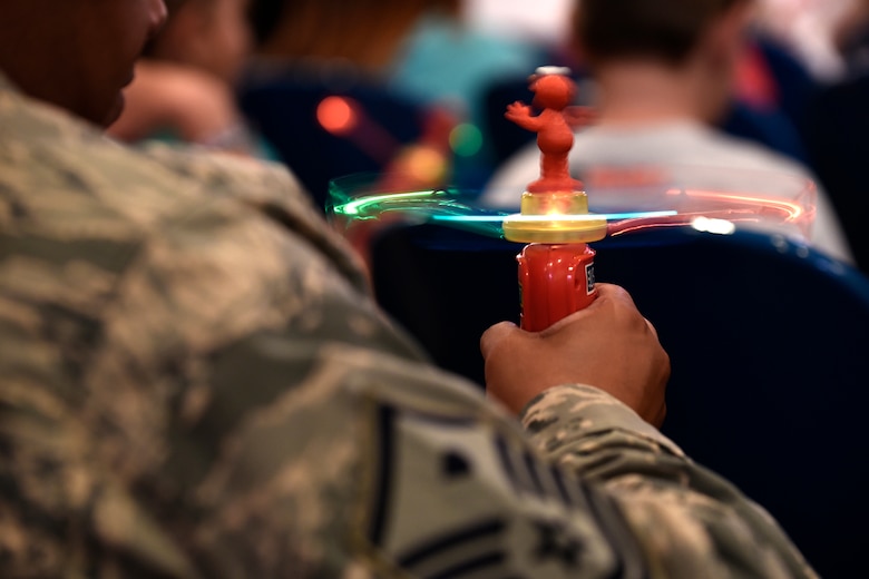 PETERSON AIR FORCE BASE, Colo. – A Peterson father plays with a light-up toy given out during the Sesame Street USO Experience at the base auditorium on Peterson Air Force Base, Colo., July 22, 2016. The tour travels the globe each year spreading a message to help military families deal with unique challenges they face.  Since its debut in 2008, the show has been performed at 149 military installations in 33 states and 11 countries. (U.S. Air Force photo by Senior Airman Rose Gudex)