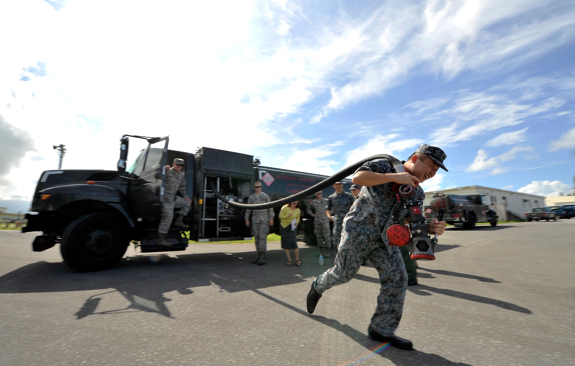 Japan Air Self Defense Force Capt. Takehiro Okabayashi, Headquarters Southwestern Composite Air Division, Naha Air Base, demonstrates pulling the hose of an R-11 fuel truck during their tour, July 21, 2016, at Kadena Air Base, Japan. The benefits of this tour for both parties are the opportunity for professional networking throughout Okinawa's fuels community and the sharing of ideas on the most effective methods and equipment for delivering jet fuel. (U.S. Air Force photo by Naoto Anazawa)