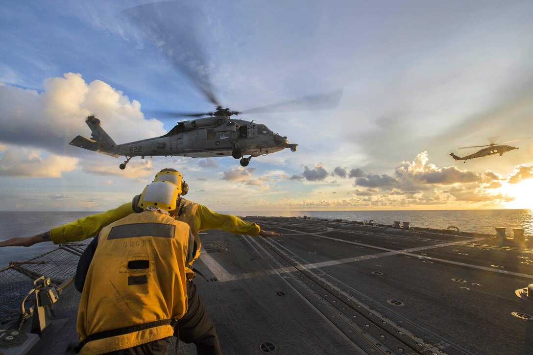 Sailors signal to an MH-60S Seahawk helicopter during visit, board, search and seizure training as it hovers over the flight deck of the USS McCampbell in the South China Sea, July 22, 2016. The McCampbell is patrolling with Carrier Strike Group 5 in the U.S. 7th Fleet area of responsibility supporting security and stability in the Indo-Asia-Pacific. Navy photo by Petty Officer 3rd Class Elesia K. Patten