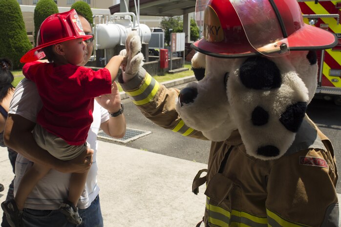 A child high-fives Sparky the Fire Dog, mascot of Marine Corps Iwakuni Air Station fire station, during the Fire and Ice ice cream social at MCAS Iwakuni, Japan, July 20, 2016. The Exceptional Family Member Program hosted the event in collaboration with the MCAS Iwakuni Fire Department at Fire Station Four, where Japanese firemen and air station residents participated in family activities. (U.S. Marine Corps photo by Lance Cpl. Donato Maffin)