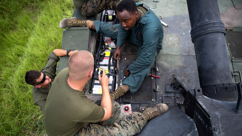 Sgt. Mark tucker and Cpl. Charles Vollmer of Fox Company, 4th Tank Battalion, work to fix the batteries in the M1A1 Abrams battle tank they sit on during a training exercise July 19, 2016. The exercise brought the reserve Marines together with elements of 2nd Tank Bn. to train in the event they deploy as one battalion in the future. 