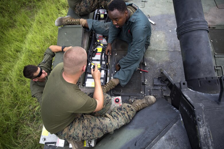 Sgt. Mark tucker and Cpl. Charles Vollmer of Fox Company, 4th Tank Battalion, work to fix the batteries in the M1A1 Abrams battle tank they sit on during a training exercise July 19, 2016. The exercise brought the reserve Marines together with elements of 2nd Tank Bn. to train in the event they deploy as one battalion in the future. (U.S. Marine Corps photo by Sgt. Matthew Callahan)