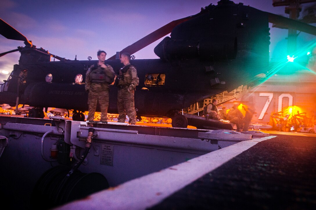 Soldiers talk next to an MH-47G Chinook helicopter on the flight deck of the aircraft carrier USS Carl Vinson in the Pacific Ocean, July 19, 2016. The helicopter is assigned to the 160th Special Operations Aviation Regiment (Airborne). Navy photo by Petty Officer 3rd Class Sean M. Castellano
