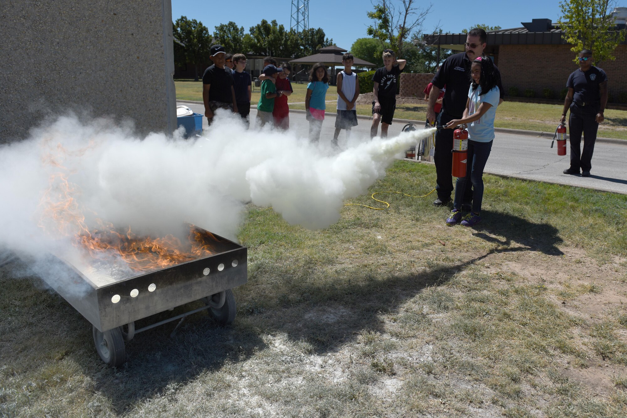 A young girl extinguishes a fire during the Junior Firefighter Camp at the Goodfellow Fire Department on Goodfellow Air Force Base, Texas, July 20, 2016. Extinguisher training took place during the week-long camp for children ages 9 to 13. (U.S. Air Force photo by Airman 1st Class Caelynn Ferguson/Released)