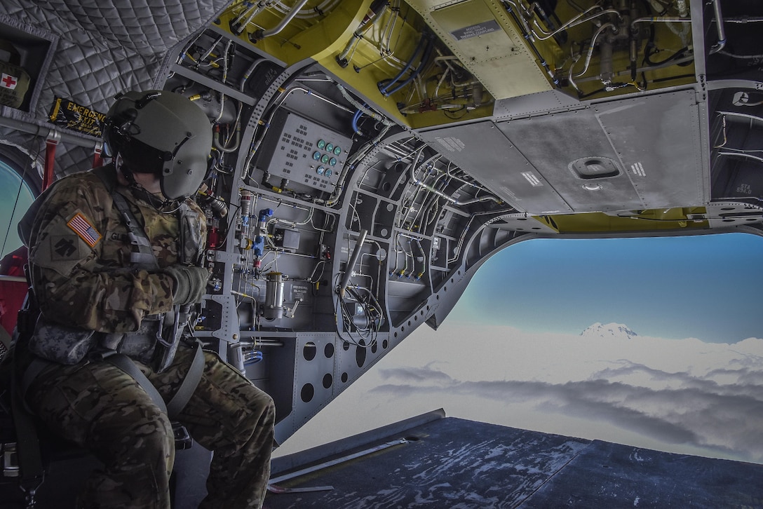 U.S. Army Reserve Sgt. Dan Glenn, 1-214th General Support Aviation Battalion, Bravo Company, communicates with fellow aircrew members during a flyover near Mount Rainier, Wash., onboard a CH-47 Chinook, July 22, 2016.  The 1-214th GSAB, has a unique mission which involves working with the Washington National Park  and provides support for search and rescue missions as well as fire rescue missions in the area.  (U.S. Army photo by Master Sgt. Marisol Walker/Released)