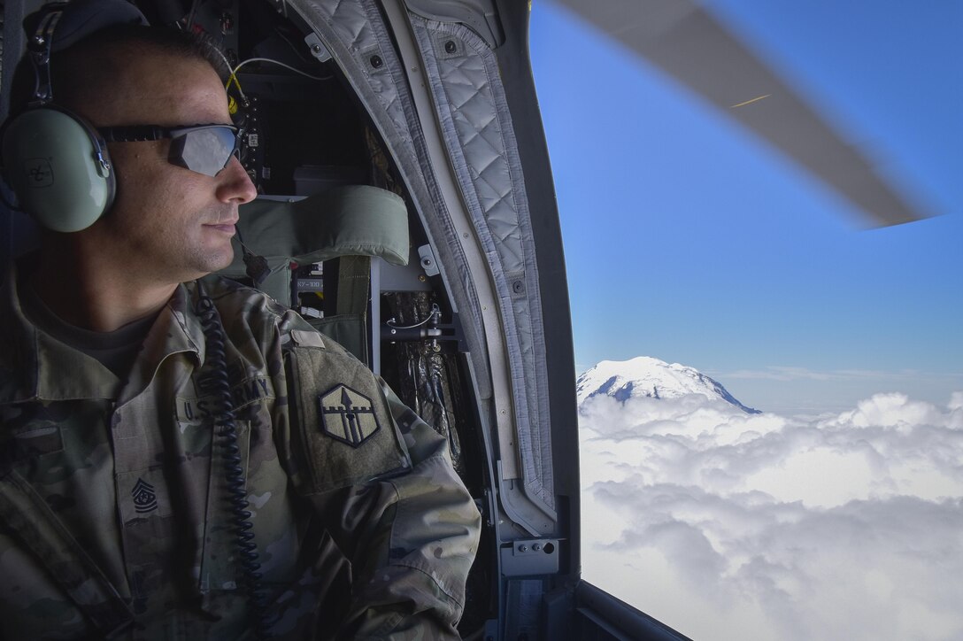 U.S. Army Reserve Command Sgt. Maj. Thomas C. Perry, 301st Maneuver Enhancement Brigade (MEB) command sergeant major, enjoys the view from a CH-47 Chinook, July 22, 2016, near the top of Mount Rainier, Washington.  Perry along with other U.S. Army Reserve soldiers participated in a flyover of Mount Rainier, Joint Base Lewis-McChord and Yakima Training Center by the U.S. Army Reserve 1-214th General Support Aviation Battalion, Bravo Company,  based out of Joint Base Lewis-McChord.  (U.S. Army photo by Master Sgt. Marisol Walker/Released)