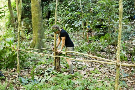 Kim Liszka, an emergency room nurse from Macungie, Pennsylvania, ties together branches with a vine to build a shelter while filming the survival competition series American Tarzan. Liszka, a former Army Reserve captain, says her prior military training helped her survive and navigate obstacles while on the remote island of Dominica. The finale airs Wednesday, July 27 at 10/9 C on the Discovery Channel.