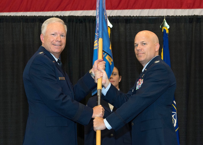 Lt. Gen. John F. Thompson, Air Force Life Cycle Management Center commander, passes the guidon to Col. Roman L. Hund during the 66th Air Base Group change of command ceremony at the base Aero Club Hangar July 26, while Hanscom Command Chief Master Sgt. Patricia L. Hickey looks on. Hund is responsible for securing, supporting and sustaining more than 5,000 active duty, Reserve and National Guard personnel, Defense Department civilians, contractors along with 130,000 retired military and spouses living in the six-state New England and New York area. (U.S. Air Force photo by Jerry Saslav)