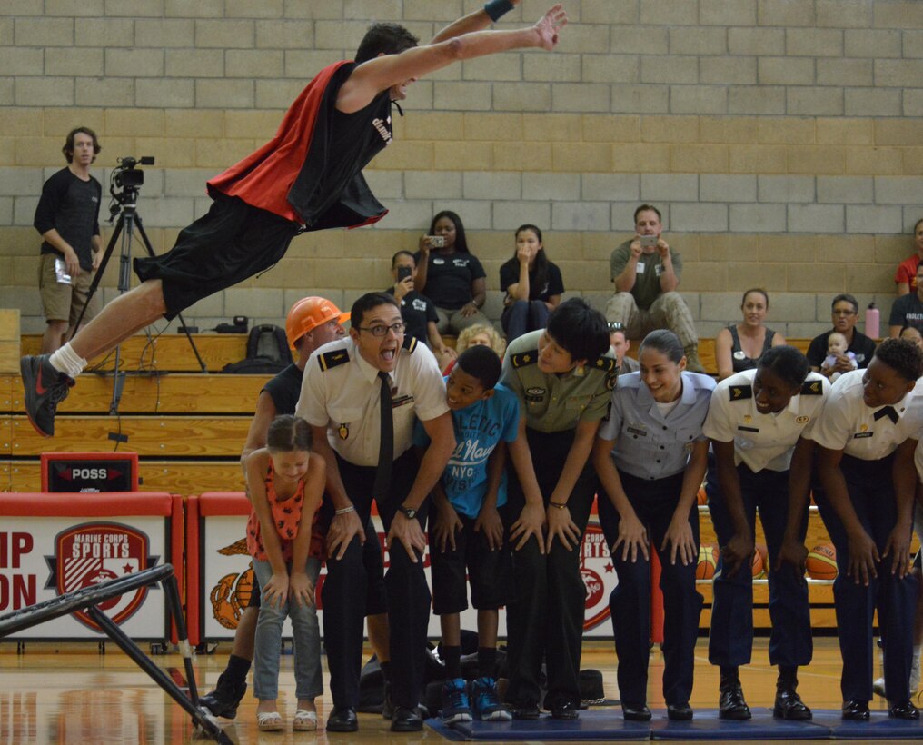 French referee Christophe Gomez and athletes from China, Germany and the U.S. -- along with two U.S. family members -- duck as a TNT Dunk Squad acrobat somersaults over their heads at end of the opening ceremony for the World Military Women's Basketball Championship at Marine Corps Base Camp Pendleton, Calif., July 25, 2016. Courtesy photo