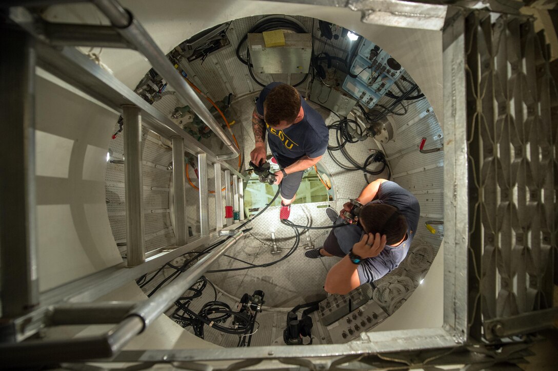 Navy divers inspect gear inside the ocean simulation facility that mimics pressurized ocean conditions at the Navy Experimental Diving Unit, Naval Support Activity Panama City Division, Panama City Beach, Fla., July 13, 2016. DoD photo by EJ Hersom