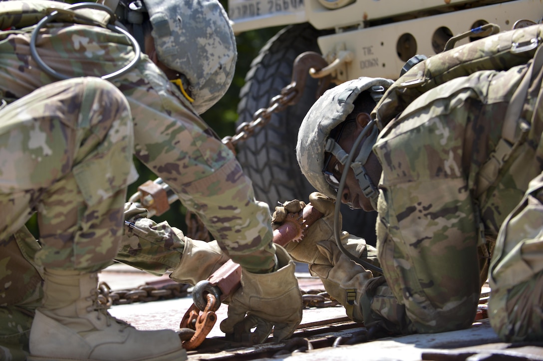 U.S. Army Pvt. James Harrington, 7th Transportation Brigade (Expeditionary) cargo specialist, wrenches chains into place to secure a High Mobility Multipurpose Wheeled Vehicle at Fort Eustis, Va., July 20, 2016. Cargo specialists are responsible for transferring or supervising the transfer of passengers, cargo and equipment to and from air, land and water. (U.S. Air Force photo by Staff Sgt. Natasha Stannard)