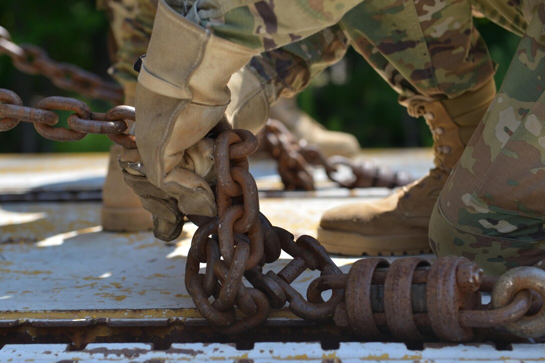 U.S. Army 7th Transportation Brigade (Expeditionary) Soldiers wrench chains into place to secure a High Mobility Multipurpose Wheeled Vehicle at Fort Eustis, Va., July 20, 2016. The 7th TB(X) is the Army’s only active component Army unit that exclusively executes logistics over-the-shore operations, for which this training prepares Soldiers. (U.S. Air Force photo by Staff Sgt. Natasha Stannard)