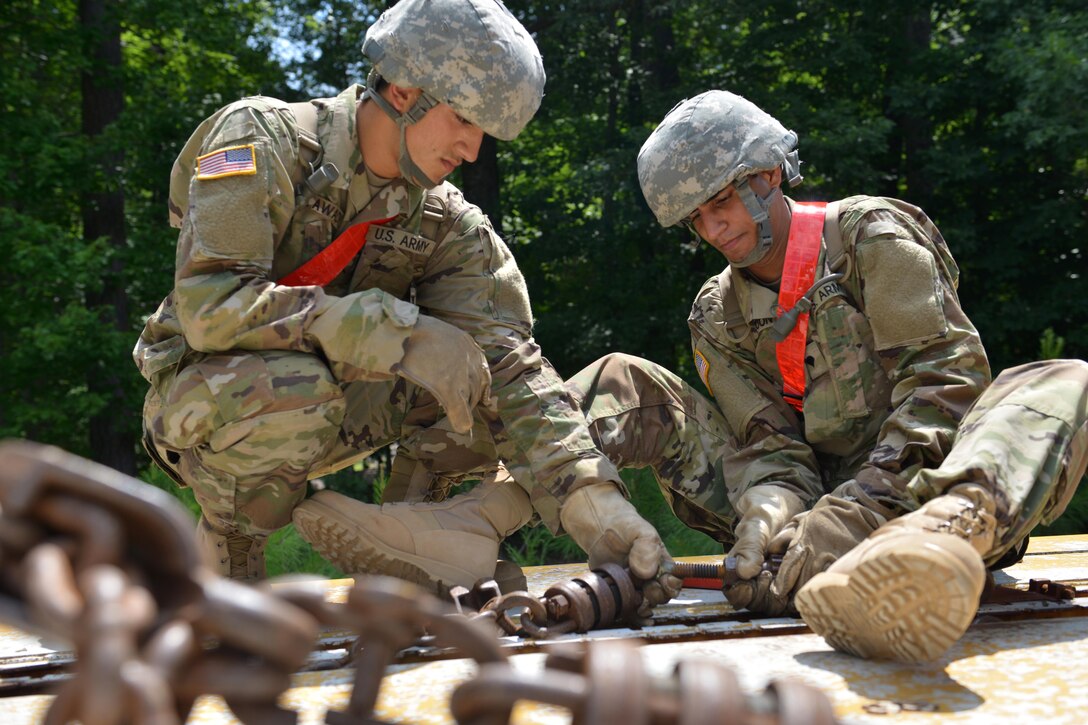 U.S. Army Pvt. Hassan Alawady and Spc. Kartik Joon, 7th Transportation Brigade (Expeditionary) cargo specialists, secure chains into place to secure cargo onto a rail car at Fort Eustis, Va., July 20, 2016. The brigade trains on various cargo loading skills to ensure constant preparation for contingency operations. (U.S. Air Force photo by Staff Sgt. Natasha Stannard)