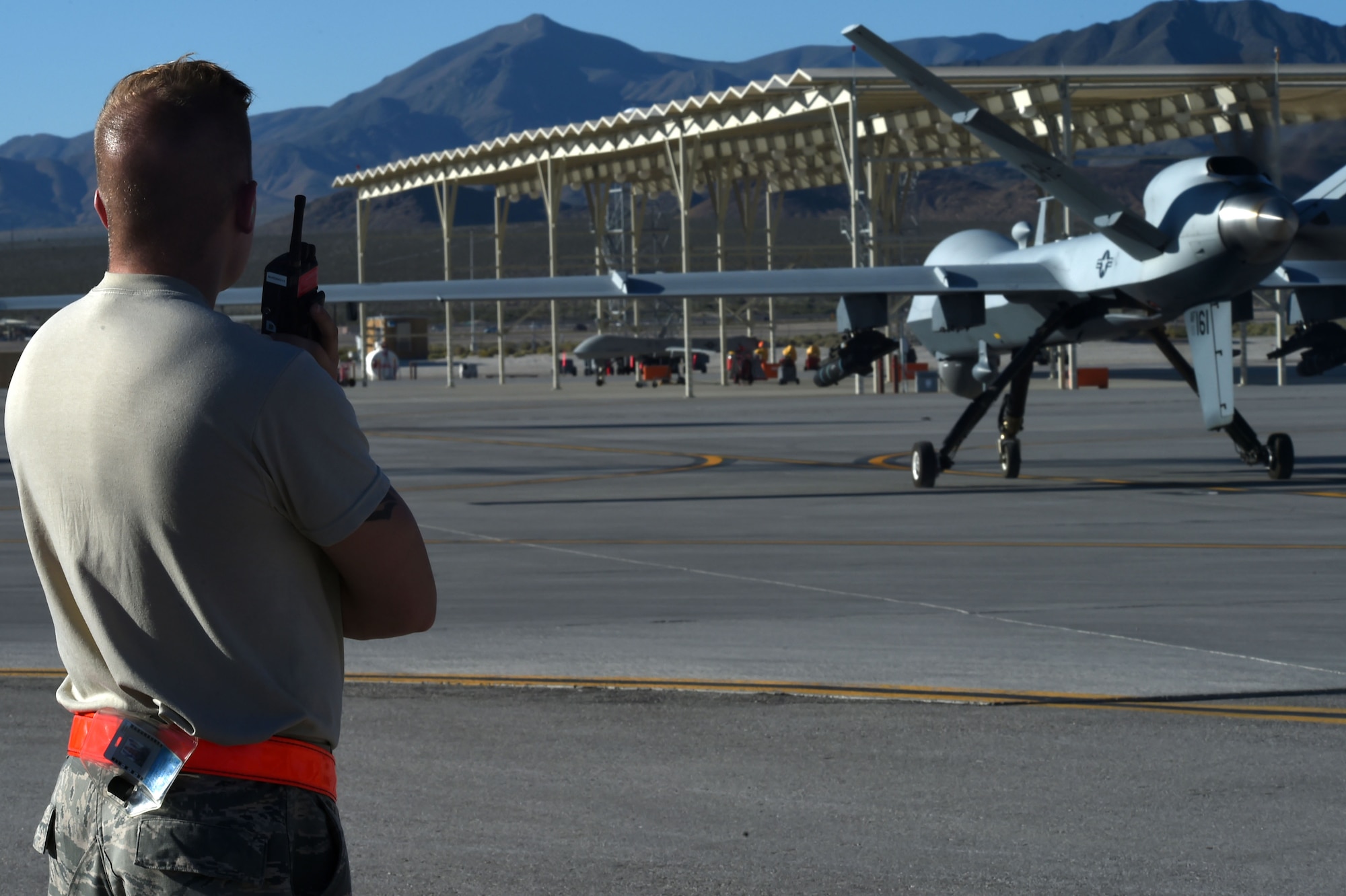 Airman 1st Class Conner, a crew chief with the 432nd Aircraft Maintenance Squadron, guides an MQ-9 Reaper onto the runway as it departs to support Red Flag 16-3, July 19, 2016, at Creech Air Force Base, Nevada.  Red Flag provides advanced combat training to ensure future success for military operations. (U.S. Air Force photo by Airman 1st Class James Thompson/Released)  
