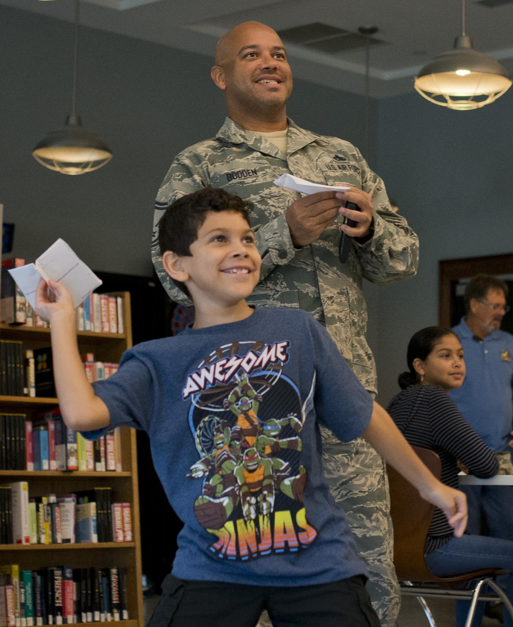 Justin and his father, Senior Master Sgt. Analdo Bodden, 33rd Maintenance Group, prepare to launch their paper airplanes together during a base reading program class July 26 at Eglin Air Force Base, Fla.  The class was taught by Ken Blackburn, Air Force Research Lab Munitions Directorate, who held the Guinness World Record for longest in-air paper airplane flight.  More than 30 kids and parents folded their planes based on Blackburn’s instructions, then filled the base’s digital library with tiny flying paper aircraft.  (U.S. Air Force photo/Samuel King Jr.)