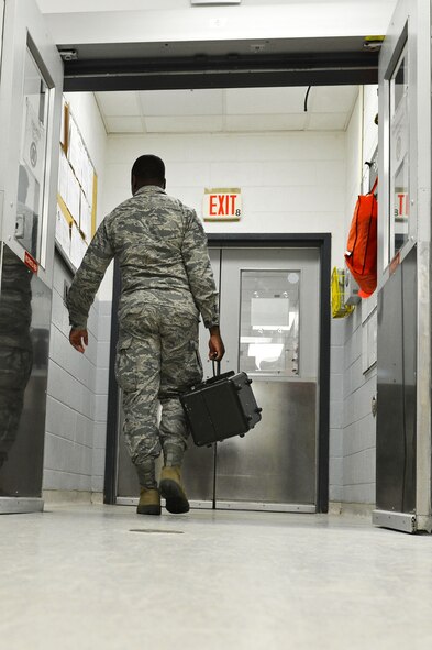 A U.S. Air Force Airman assigned to the 20th Component Maintenance Squadron precision measurement equipment laboratory flight carries a sealed piece of support equipment toward the exit of the PMEL laboratory at Shaw Air Force Base, S.C., July 21, 2016. Throughout a work day PMEL Airmen move all calibrated gear to the customer pick-up center. (U.S. Air Force photo by Airman 1st Class Christopher Maldonado)