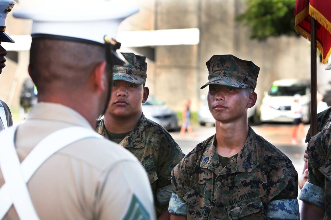 A JROTC Cadet receives instruction on close order drill from Sgt. Antonio Garay, a field radio operator and color sergeant with 3rd Marine Division during Guam's annual Liberation Day Parade July 21, 2016. The color guard marched in the parade for the first time since 3rd Marine Division liberated Guam 72 years ago. The legacy between past and present Marines and Sailors of 3rd Marine Division lives on through events such as the annual Liberation Day Parade.