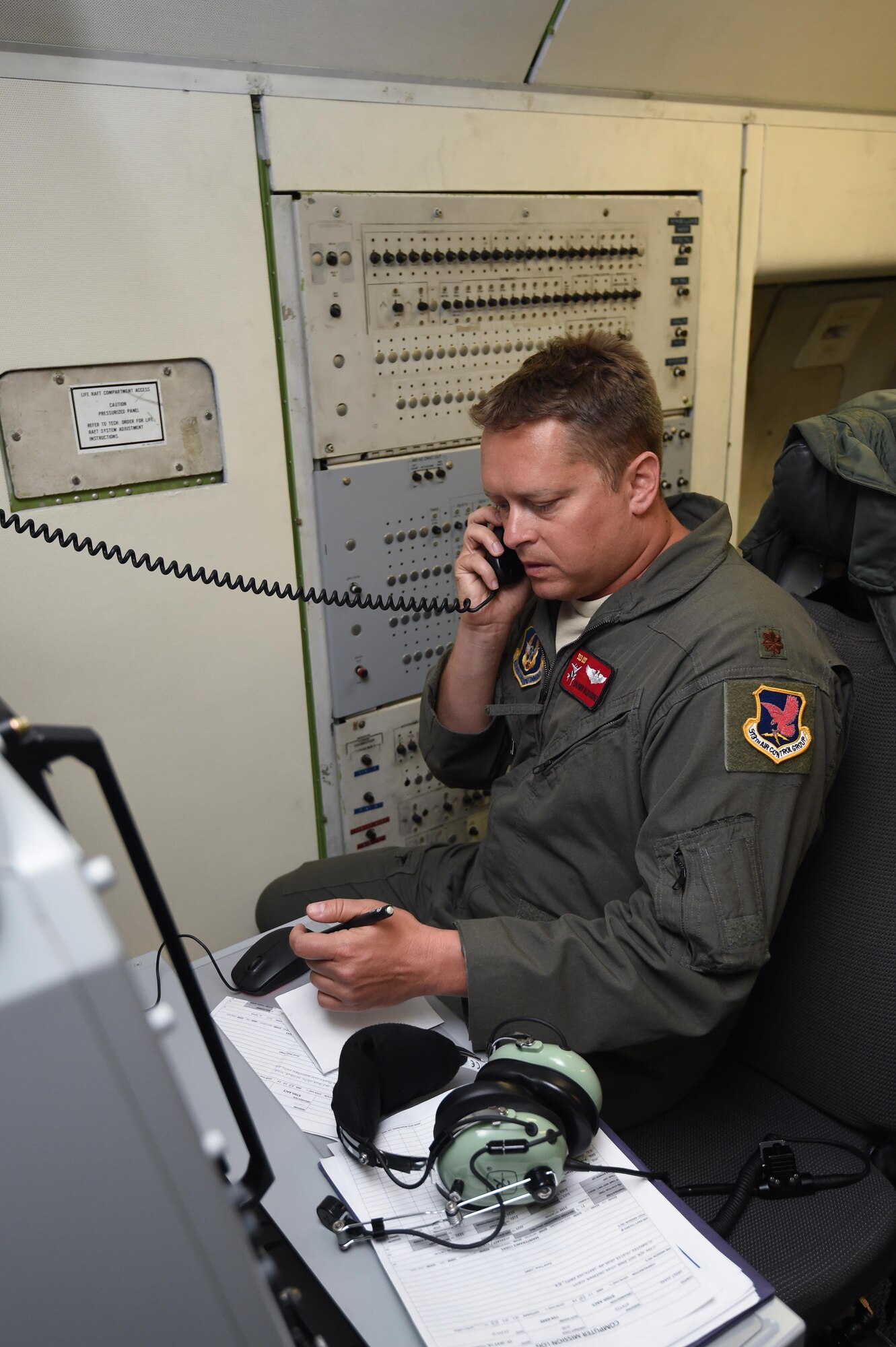 Maj. Shawn Kilbourne, a pilot assigned to the 513th Operations Support Squadron, talks on a satellite phone July 23, 2016, aboard an E-3 Sentry near the Hawaiian Islands during a mission in support of Rim of the Pacific 2016. More than 125 Airmen from the 513th Air Control Group and 552nd Air Control Wing are deployed to Hawaii in support of the RIMPAC 2016 exercise. Twenty-six nations, more than 40 ships and submarines, more than 200 aircraft and 25,000 personnel are participating in RIMPAC from June 30 to Aug. 4, in and around the Hawaiian Islands and Southern California. The world's largest international maritime exercise, RIMPAC provides a unique training opportunity that helps participants foster and sustain the cooperative relationships that are critical to ensuring the safety of sea lanes and security on the world's oceans. RIMPAC 2016 is the 25th exercise in the series that began in 1971. (U.S. Air Force photo by 2nd Lt. Caleb Wanzer)