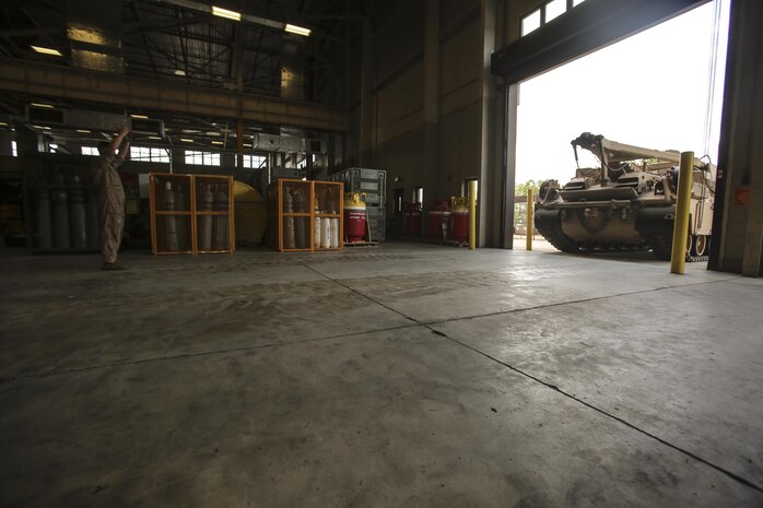 A Marine with 2nd Maintenance Battalion helps ground guide an M88 Recovery Vehicle on to the floor to be repaired at Camp Lejeune, N.C., July 21, 2016. 2nd Maint. Bn. recently received the Chesty Puller Award, the Ground Safety Award and the Department of Defense Maintenance Award for the Marines excelling at their jobs individually and collectively. (U.S. Marine Corps photo by Lance Cpl. Miranda Faughn/Released)