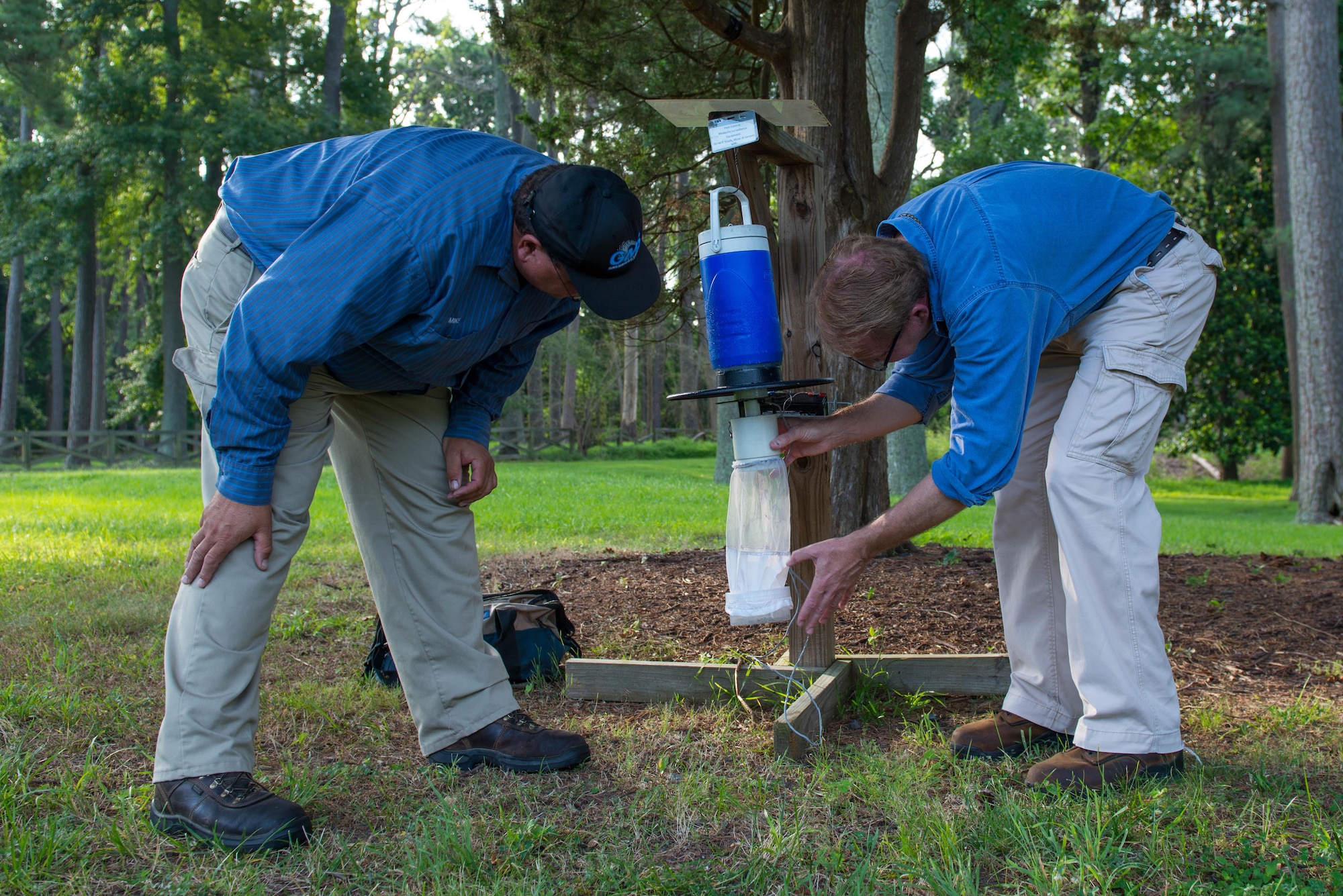 Tim Christensen, 733rd Civil Engineer Division integrated pest management coordinator, and Michael Parise, base operation services pest control contractor, check a carbon dioxide and light trap at Magnolia Park at Fort Eustis, Va., July 13, 2016. The traps are located in heavy populated areas on Ft. Eustis to monitor the mosquito population and count the number of female mosquitoes. (U.S. Air Force photo by Staff Sgt. J.D. Strong II) 
