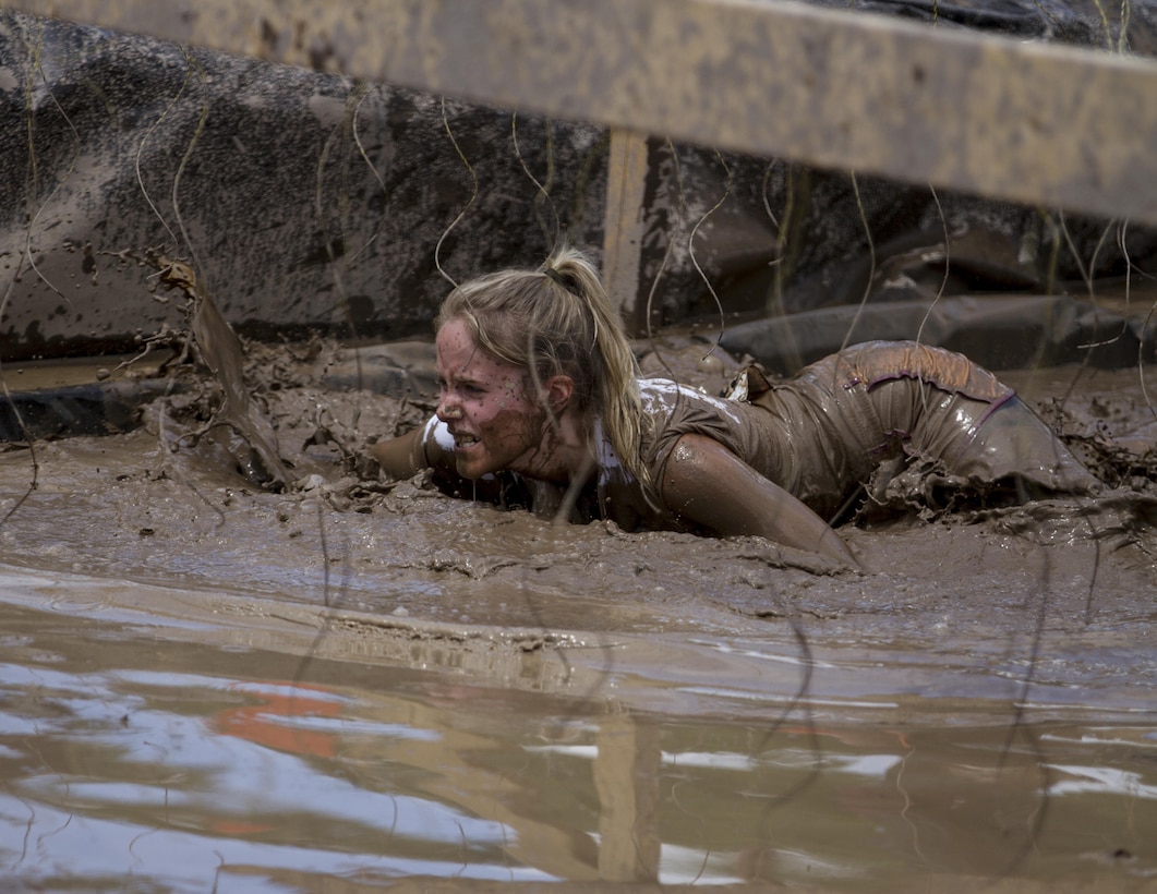 A particpant low crawls through the mud on the Electric Eel obstacle while trying to avoid the dangling wires that are putting out 10,000 volts of electricity during this year's Twin Cities Tough Mudder in Hugo, MN. In order to complete most obstacles in the Tough Mudder, participants must rely on one another for team work and support. (U.S. Army photo by Staff Sgt. Cliff Coy)