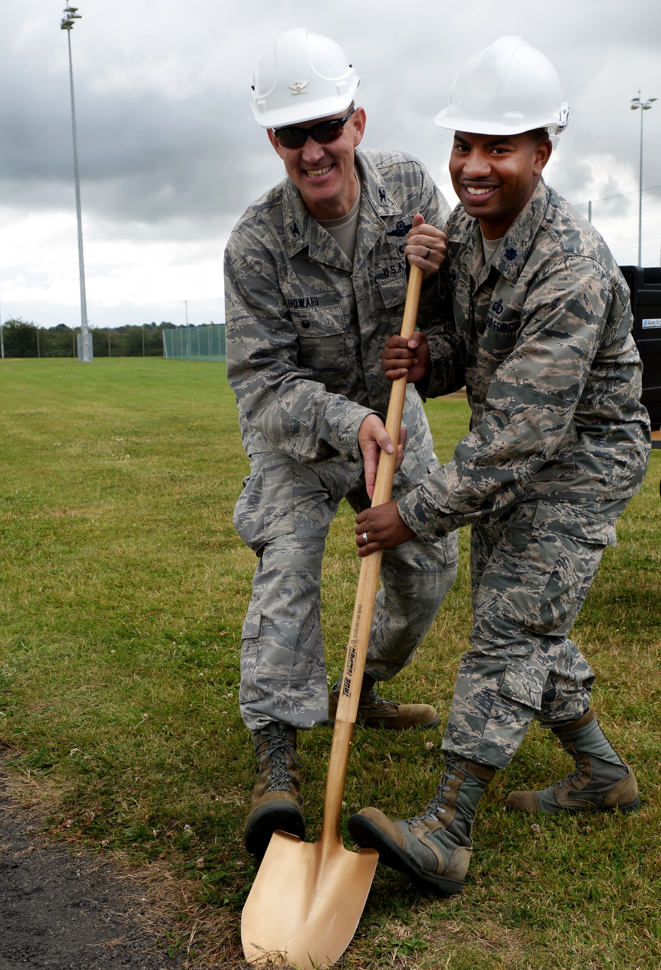 U.S. Air Force Col. John Howard, left, 100th Air Refueling Wing vice commander, and Lt. Col John Ball, 100th Force Support Squadron commander, shovel into the ground during a ceremony July 27, 2016, on RAF Mildenhall, England. The ground-breaking ceremony was held to celebrate the beginning of construction for a new track on the south side of base. (U.S. Air Force photo by Airman 1st Class Tenley Long)