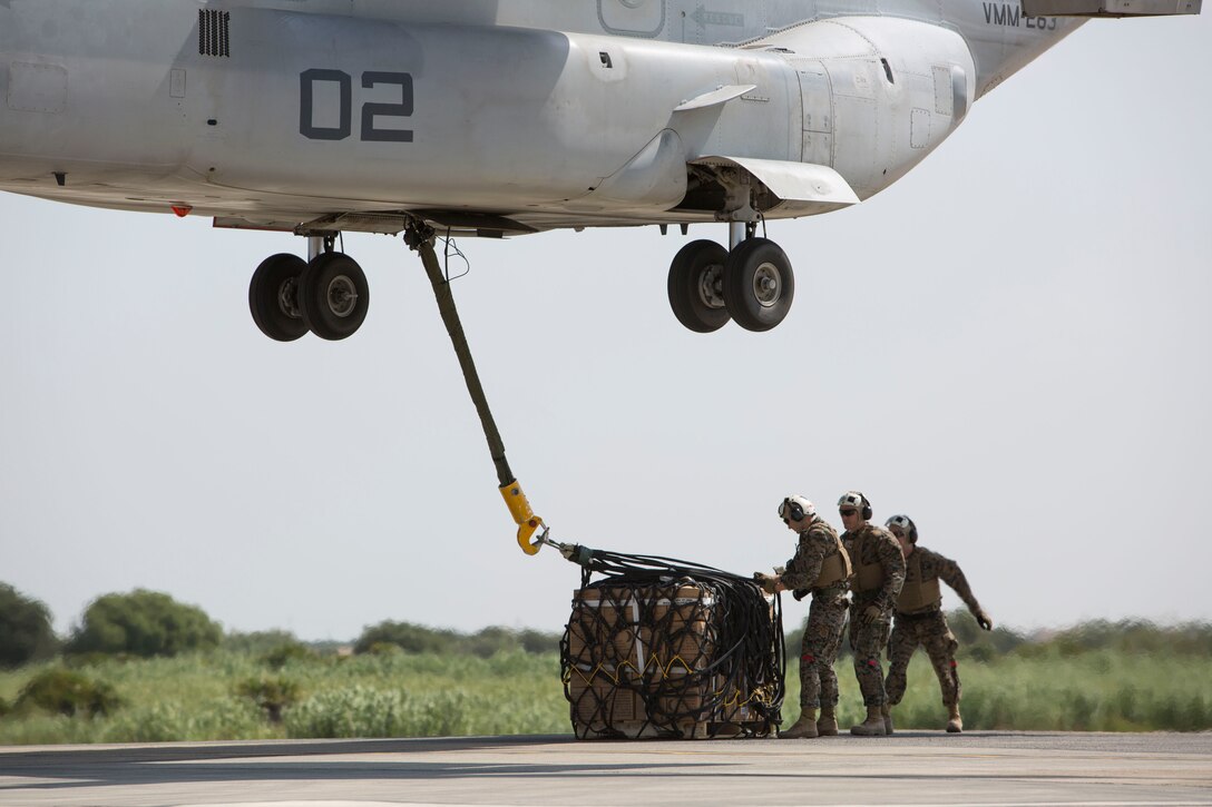 Landing support specialists with Combat Logistics Battalion 2, Special Purpose Marine Air-Ground Task Force-Crisis Response-Africa, adjust the straps on a 1,098 pound pallet of Meals, Ready to Eat to an MV-22B Osprey during a helicopter support team exercise aboard Naval Station Rota, Spain, July 6, 2016. External lift training prepares the Marines to efficiently attach cargo to the aircraft and helps qualify air crew in the mission-essential task of rapid insertion and extraction in a possible crisis response scenario. (U.S. Marine Corps photo by Staff Sgt. Tia Nagle/Released)