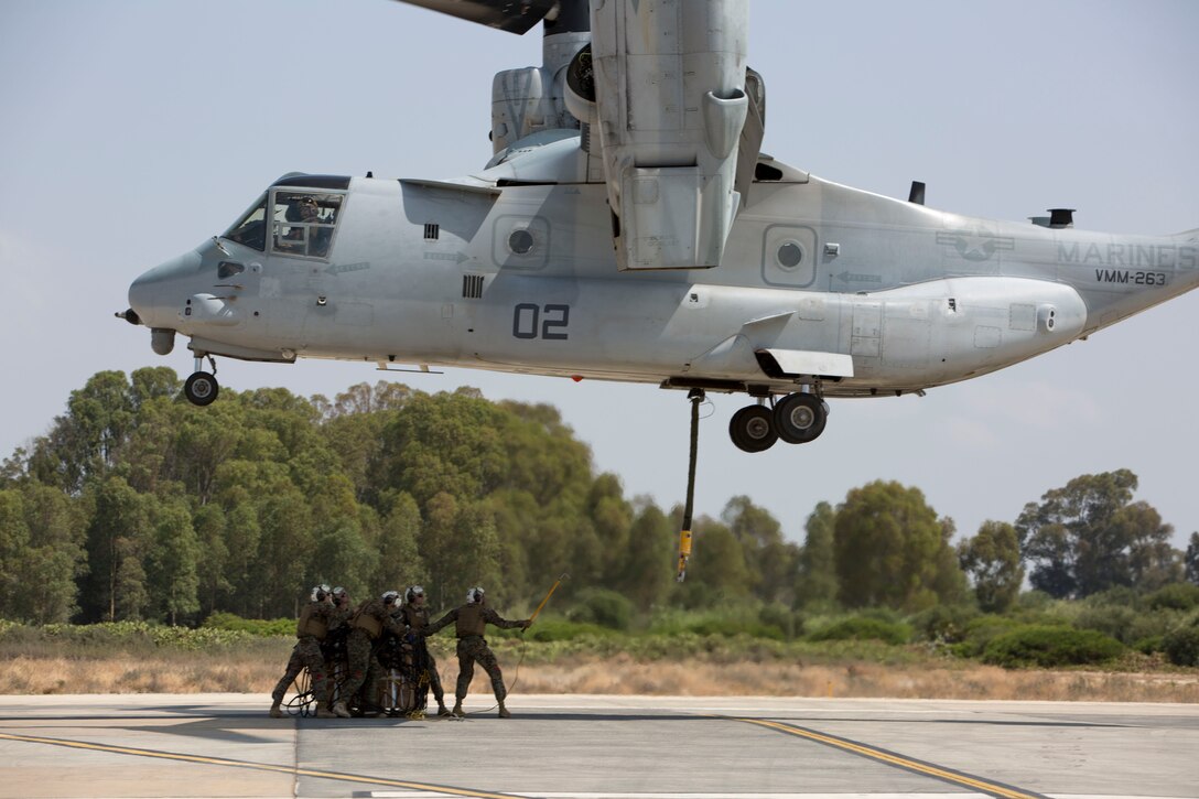 Landing support specialists with Combat Logistics Battalion 2, Special Purpose Marine Air-Ground Task Force-Crisis Response-Africa, prepare to attach a 1,098 pound pallet of Meals, Ready to Eat to an MV-22B Osprey during a helicopter support team exercise aboard Naval Station Rota, Spain, July 6, 2016. External lift training prepares the Marines to efficiently attach cargo to the aircraft and helps qualify air crew in the mission-essential task of rapid insertion and extraction in a possible crisis response scenario. (U.S. Marine Corps photo by Staff Sgt. Tia Nagle/Released)