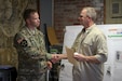 Butlerville, Ind. – Maj. Adam Weece, Exercise News Day Rotation 5 officer in charge, congratulates - Master Sgt. Brad Staggs, Atterbury-Muscatatuck public affairs noncommissioned officer in charge, for his hard work and dedication. Exercise News Day is a training exercise designed to sharpen the skills of photo and broadcast journalist during the Soldiers from the 205th Press Camp Headquarters and subordinate detachments annual training July 15-29, 2016.