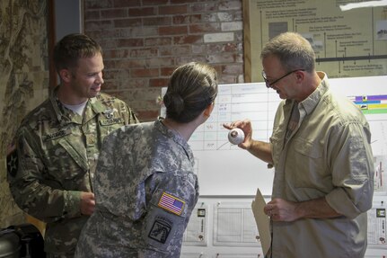 Butlerville, Ind. - Master Sgt. Brad Staggs, Atterbury-Muscatatuck public affairs noncommissioned officer in charge, and avid Astros fan, admires his baseball signed by the fifth rotation of Exercise News Day team members alongside Maj. Adam Weece, Exercise News Day Rotation 5 officer in charge, and Maj. Jennifer Mack, mission commander. Exercise News Day is a training exercise designed to sharpen the skills of photo and broadcast journalist during the Soldiers from the 205th Press Camp Headquarters and subordinate detachments annual training July 15-29, 2016.