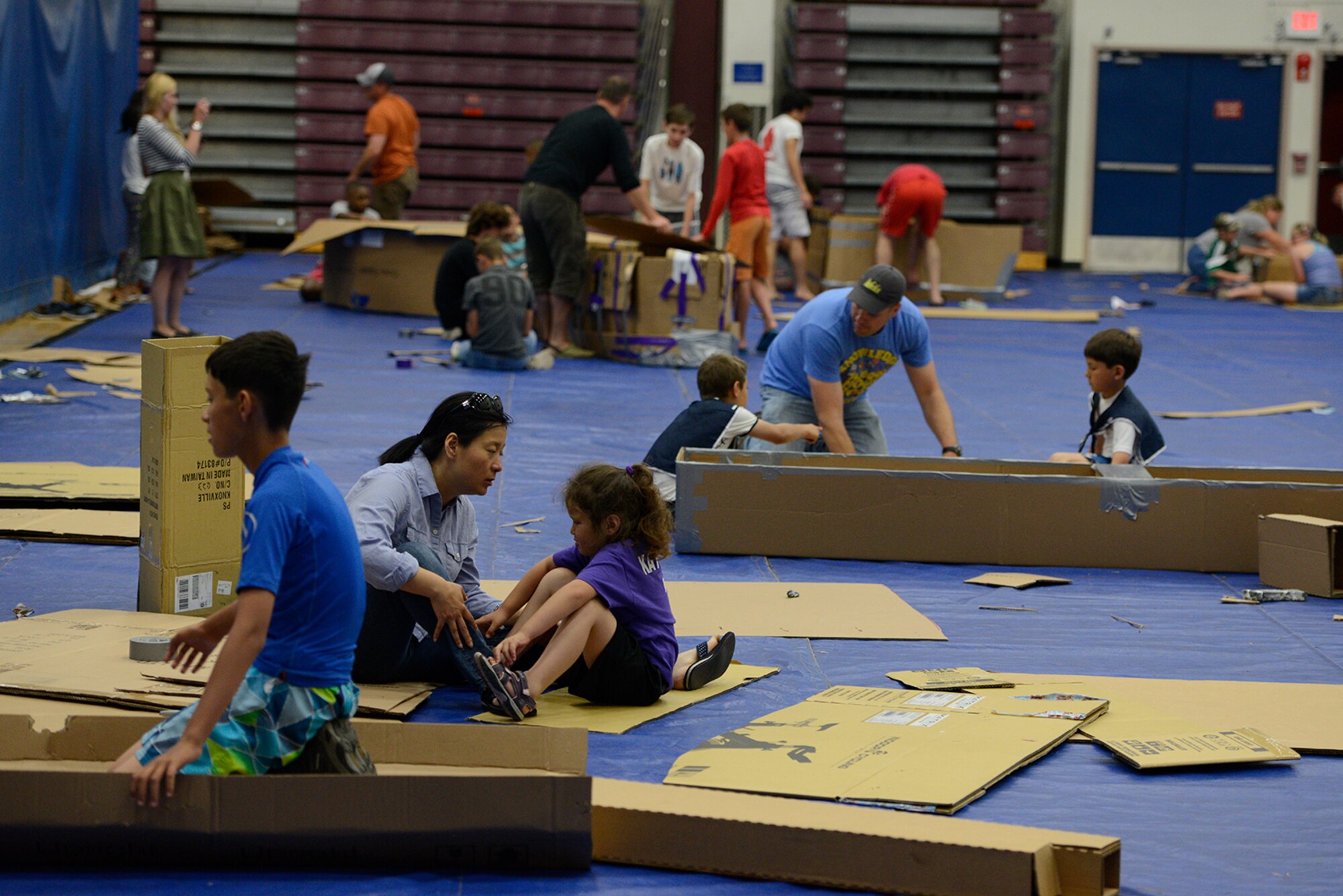 Joint Base Elmendorf-Richardson boat builders apply tape to cardboard to create boats at the Build-A-Boat competition at Buckner Physical Fitness Center at JBER, Alaska, July 23, 2016. The cardboard used in the competition was provided though a sponsorship from a local vendor. (U.S. Air Force photo by Airman 1st Class Javier Alvarez)