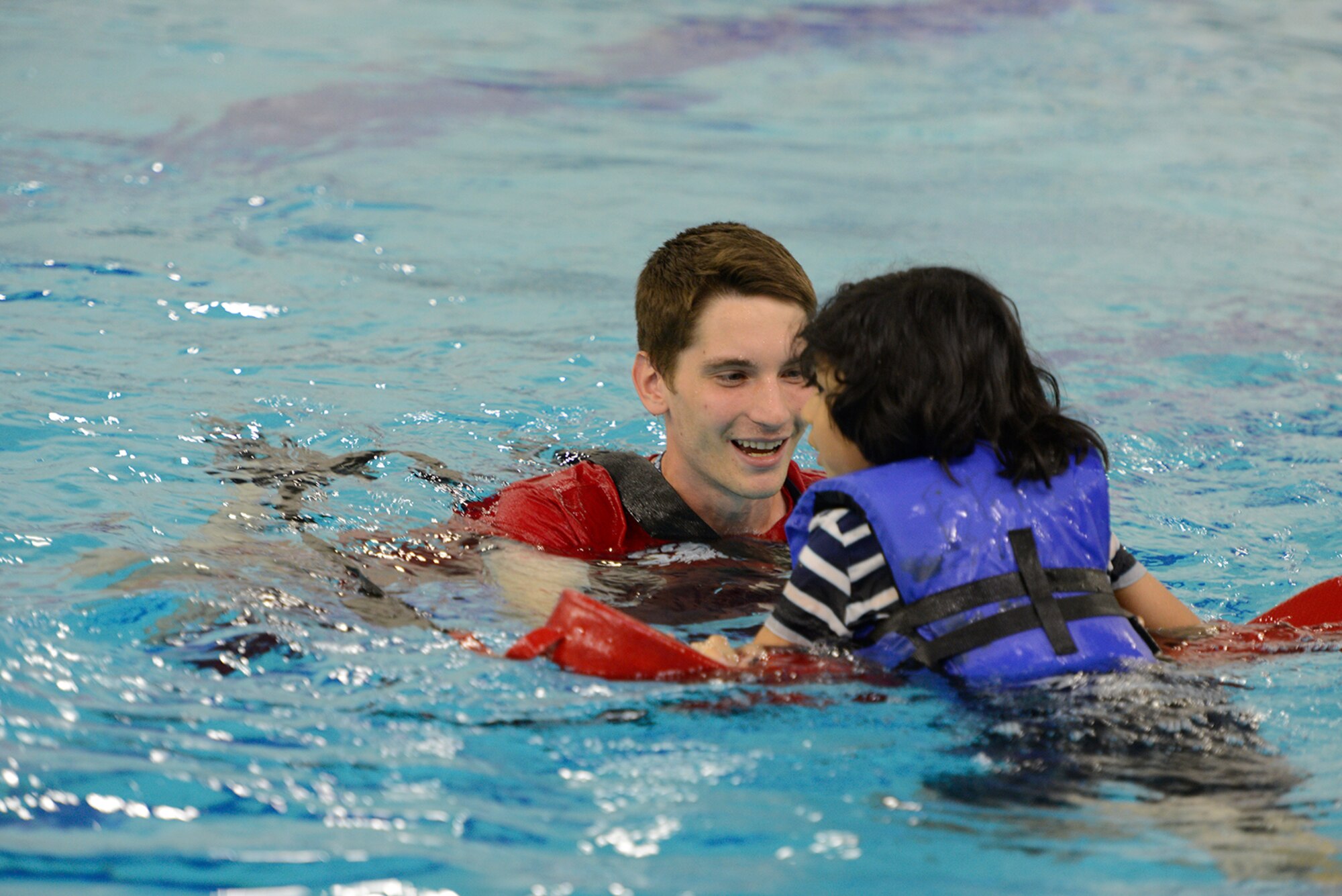 Griffin Dunn, a life guard at Buckner Physical Fitness Center, helps a victim from a capsized cardboard boat at the Build-A-Boat competition at Buckner PFC, at Joint Base Elmendorf-Richardson, Alaska, July 23, 2016. Competitors had one hour to build their cardboard vessels. (U.S. Air Force photo by Airman 1st Class Javier Alvarez)