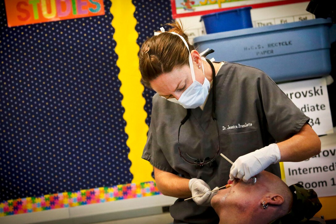 Air Force Maj. Jessica Bramlette applies a numbing agent to a patient's mouth during the Greater Chenango Cares Innovative Readiness Training at the Homer Intermediate School in Homer, N.Y., July 20, 2016. Bramlette is a dentist assigned to the New Jersey Air National Guard's 177th Medical Group. Air National Guard photo by Tech. Sgt. Matt Hecht